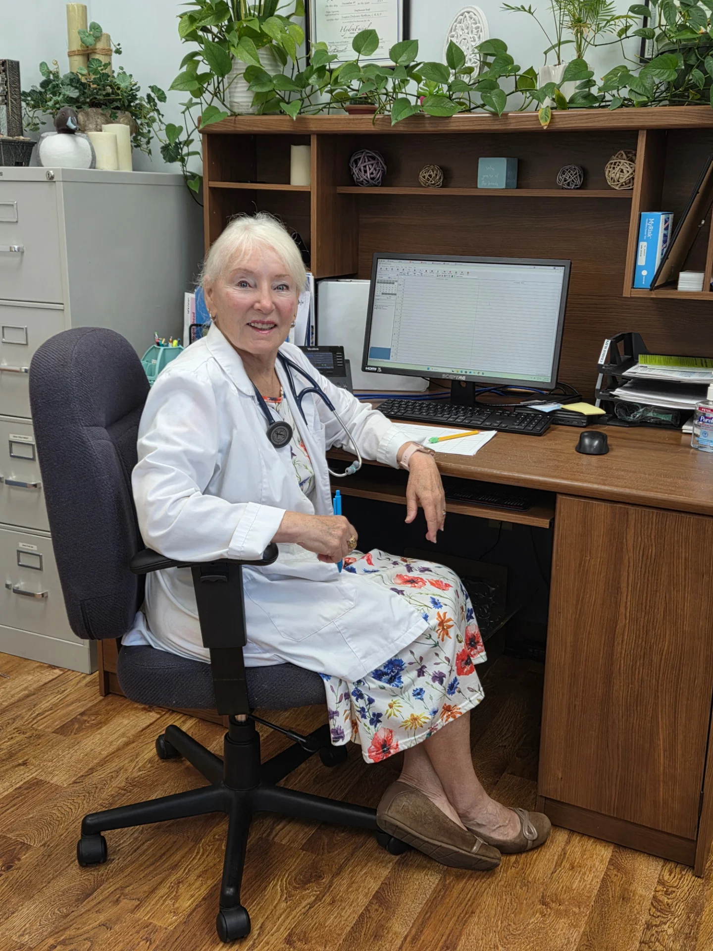 Susan Delean-Botkin at her clinic wearing a white coat and stethoscope